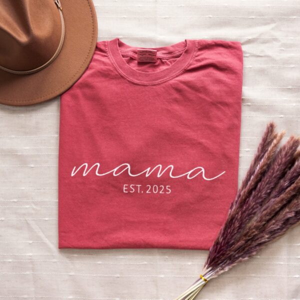 Crimson Comfort Colors Mama T-Shirt with white embroidered 'mama EST. 2025', folded with rustic decor.