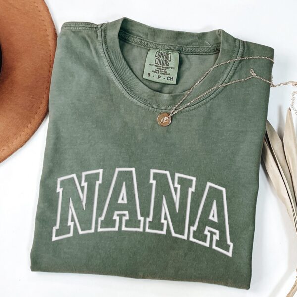 Comfort Colors Moss Nana T-Shirt with bold white varsity block letters embroidery.