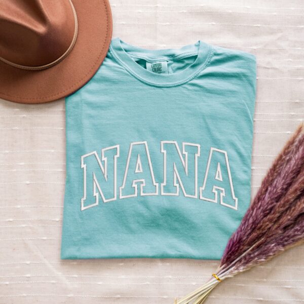 Comfort Colors Chambray Nana T-Shirt with large white varsity block letters embroidery.