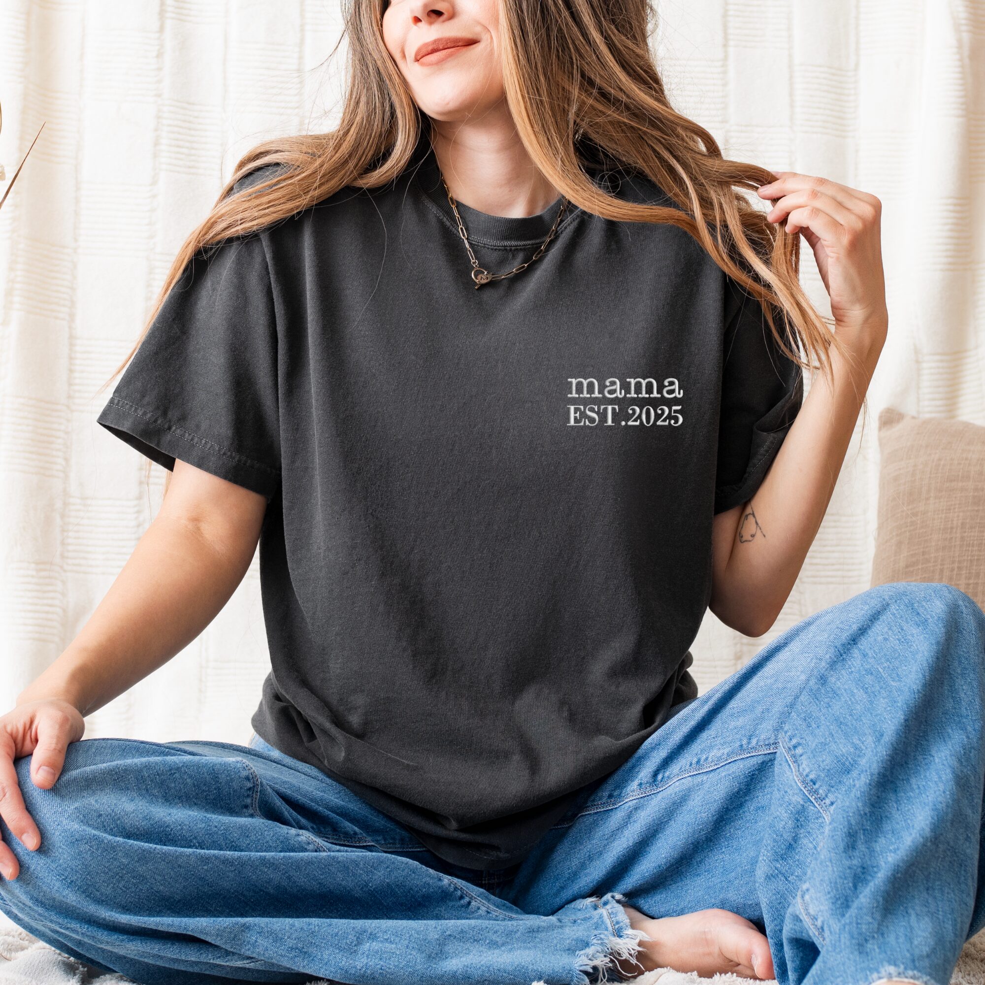 Graphite Comfort Colors Mama T-Shirt worn by woman sitting cross-legged, white 'mama EST. 2025' embroidery.