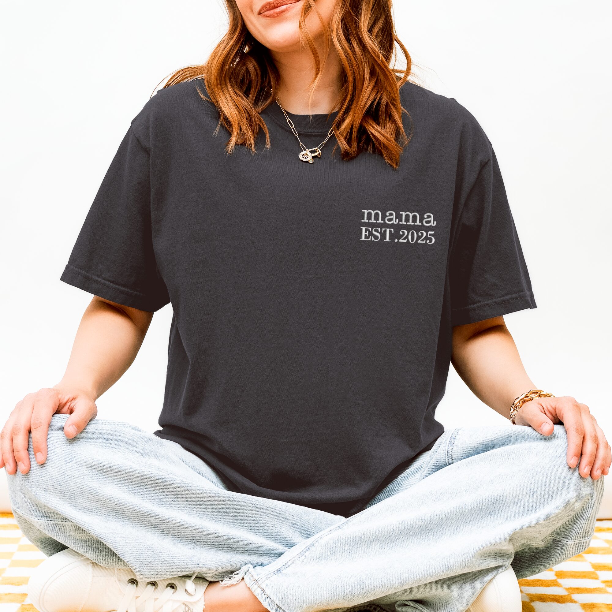 Graphite Comfort Colors Mama T-Shirt worn by woman sitting cross-legged, white 'mama EST. 2025' embroidery.
