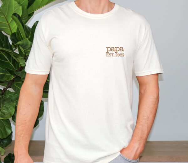 Ivory Comfort Colors Minimalist Papa Shirt worn by man, brown “papa EST. 2025” embroidery on chest.